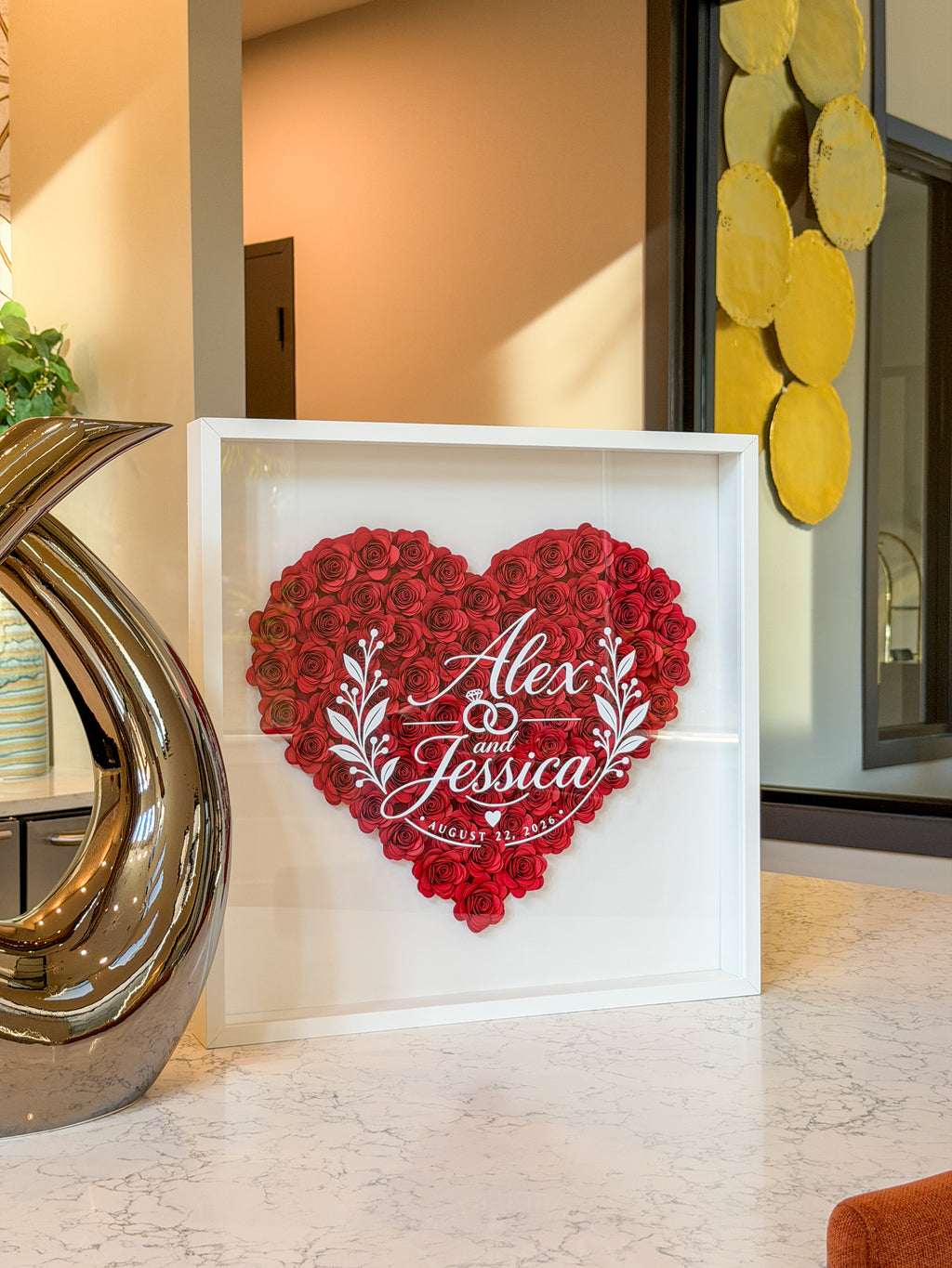 White shadow box frame of handmade paper roses styled on a kitchen counter