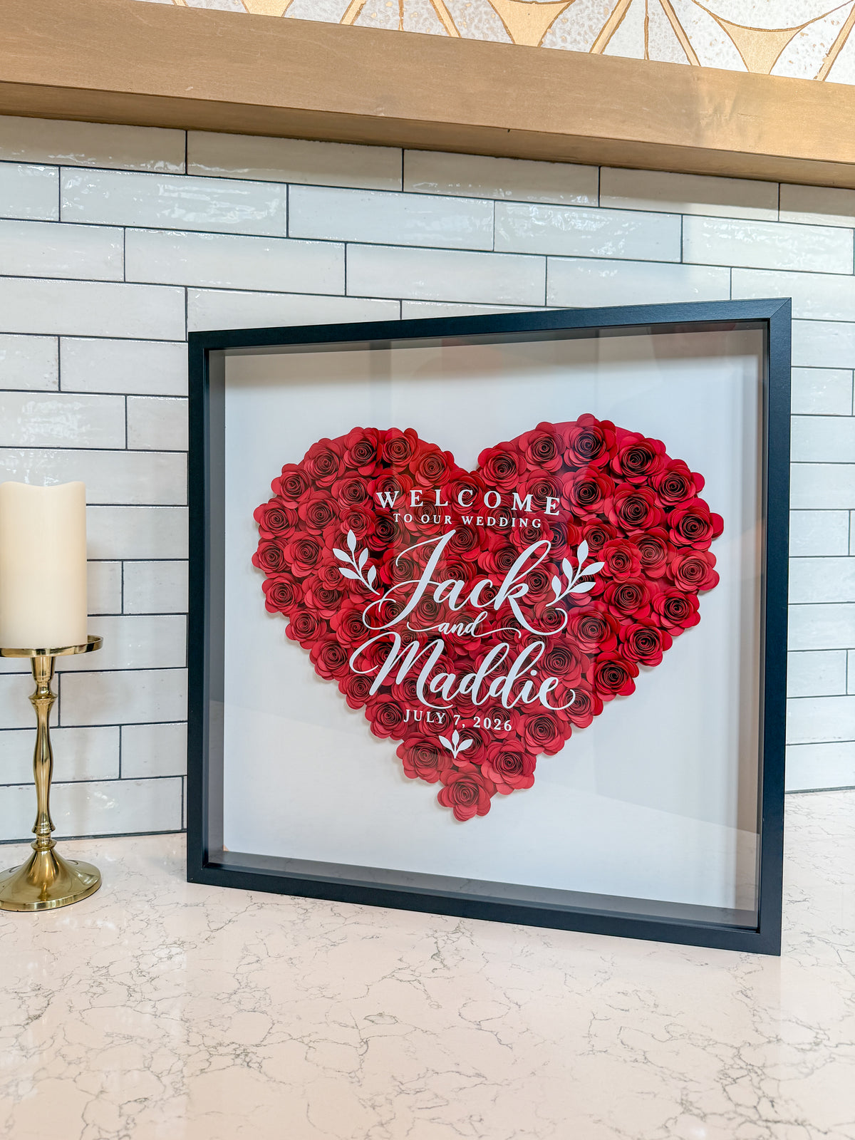 Black frame wedding flower frame with a heart of red paper roses, styled on a kitchen counter